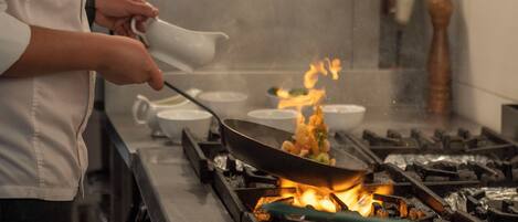 Un chef cocina con un wok en una hornilla, rodeado de varios cuencos.