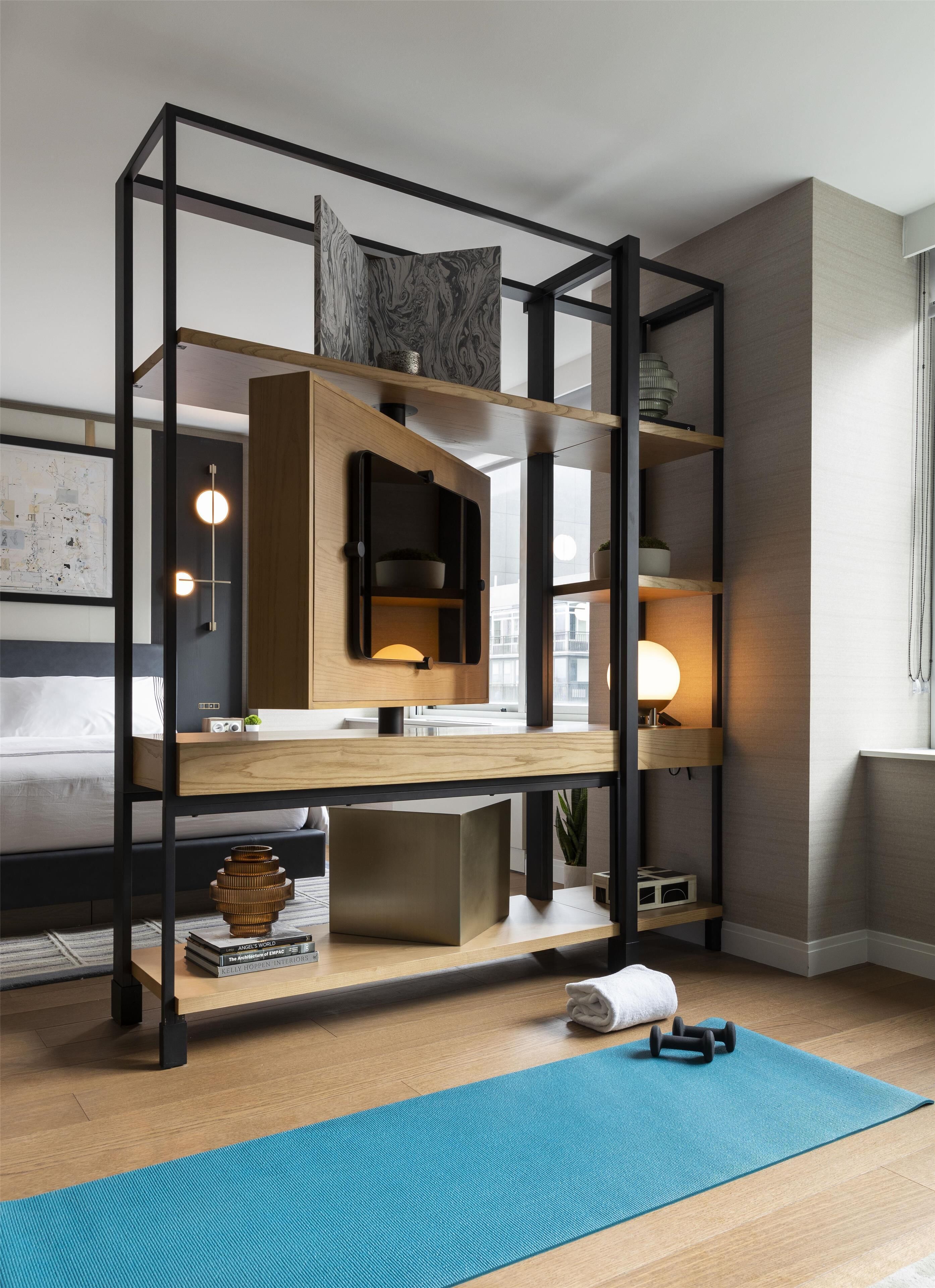 A modern bedroom with a bunk bed, a desk with a lamp, a small plant, and a yoga mat.