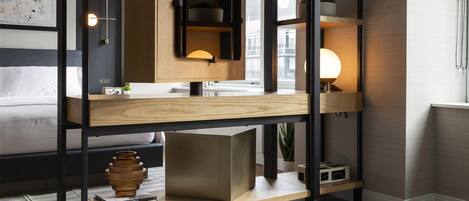 A modern bedroom with a bunk bed, a desk with a lamp, a small plant, and a yoga mat.
