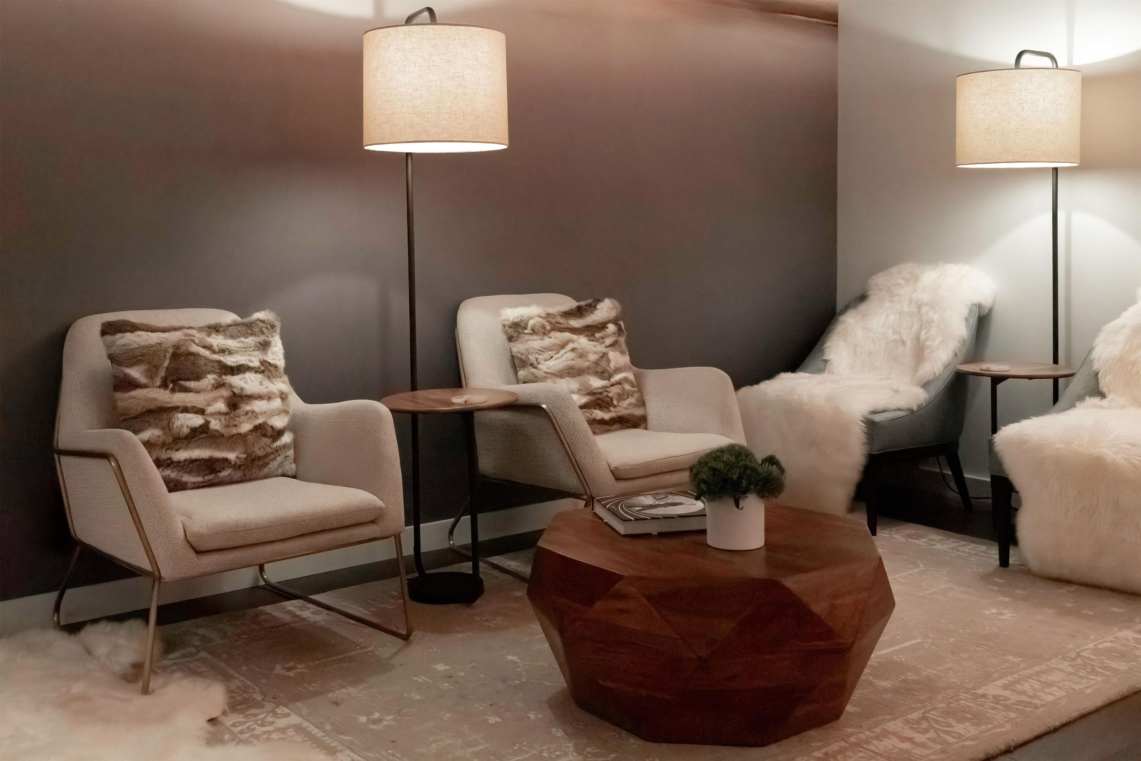 A modern living room with two armchairs, a coffee table, and two floor lamps.