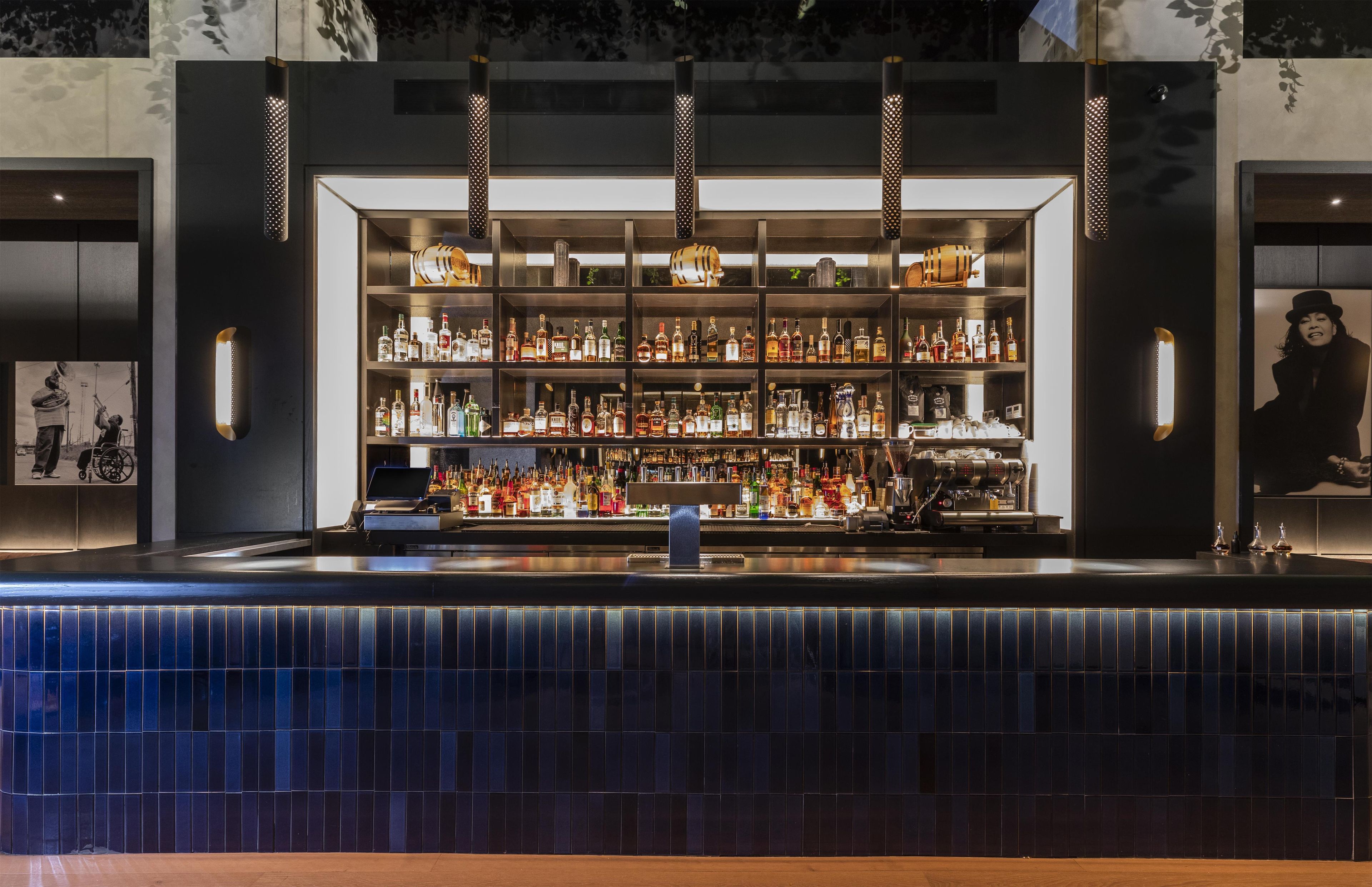 A bar area with shelves of liquor bottles, a coffee machine, and a tiled counter.