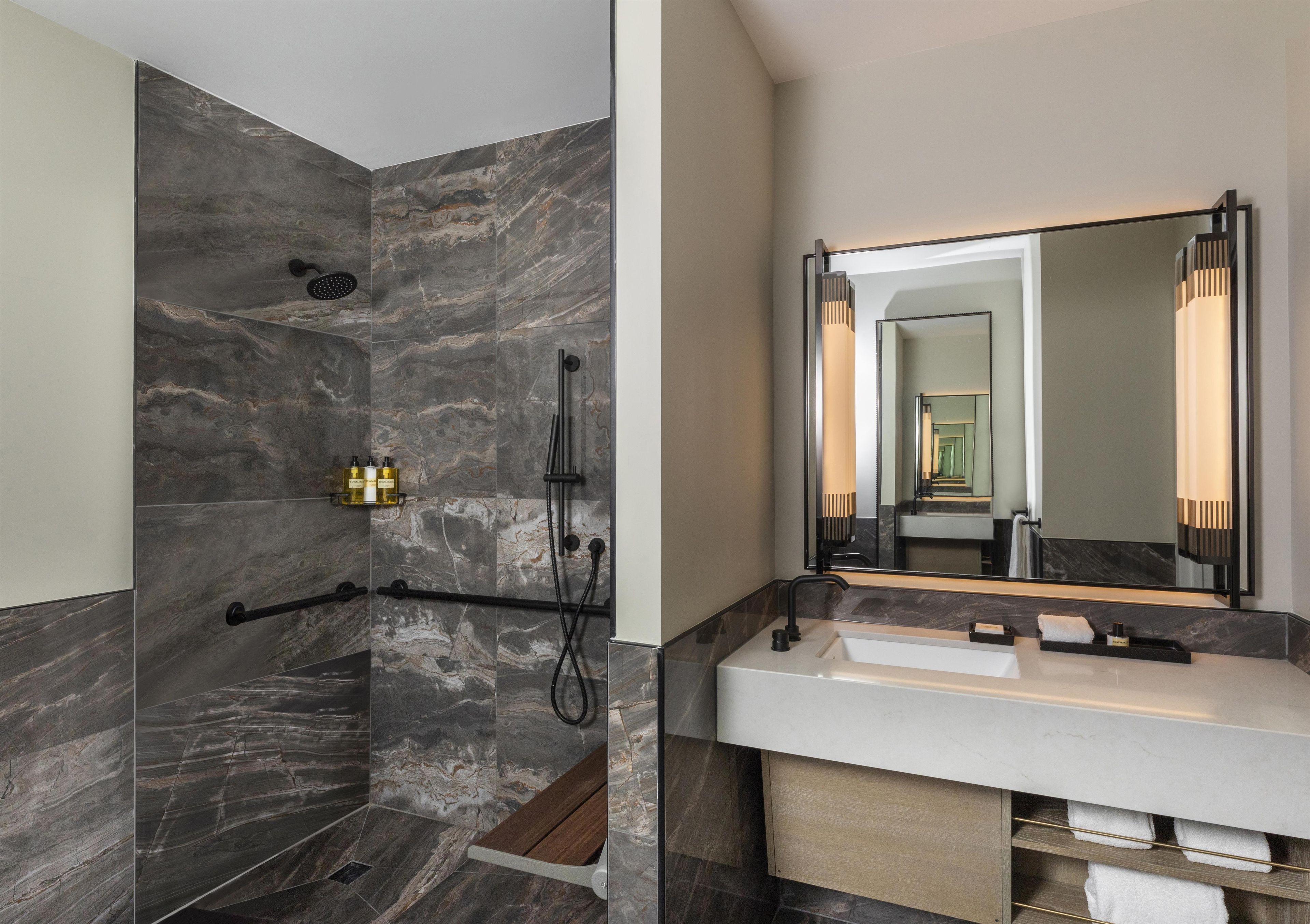 Un bagno moderno con doccia, lavabo e uno specchio grande.
