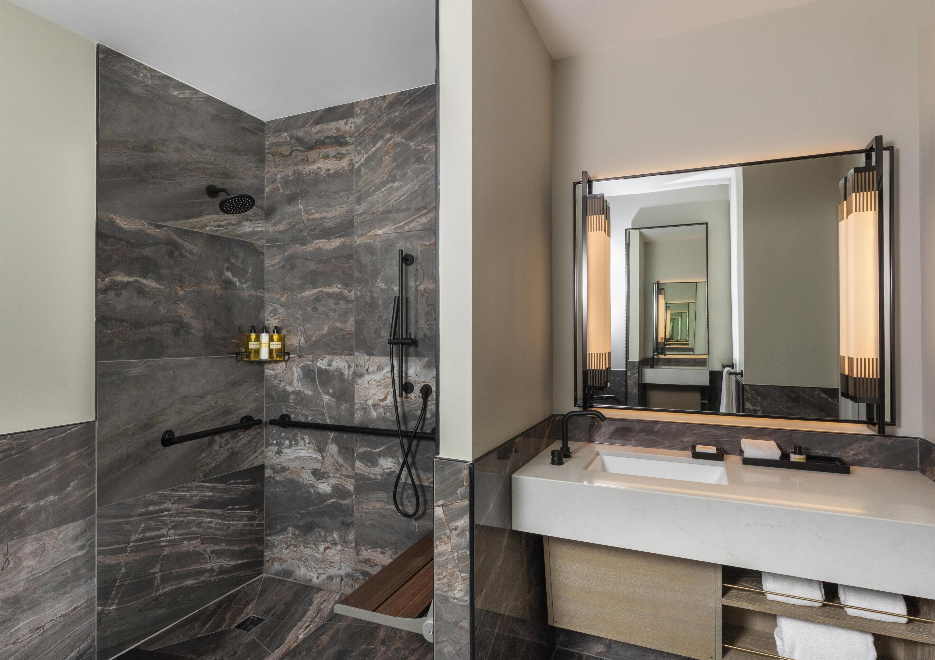 A modern bathroom with a shower, a large mirror, and a vanity with a sink.