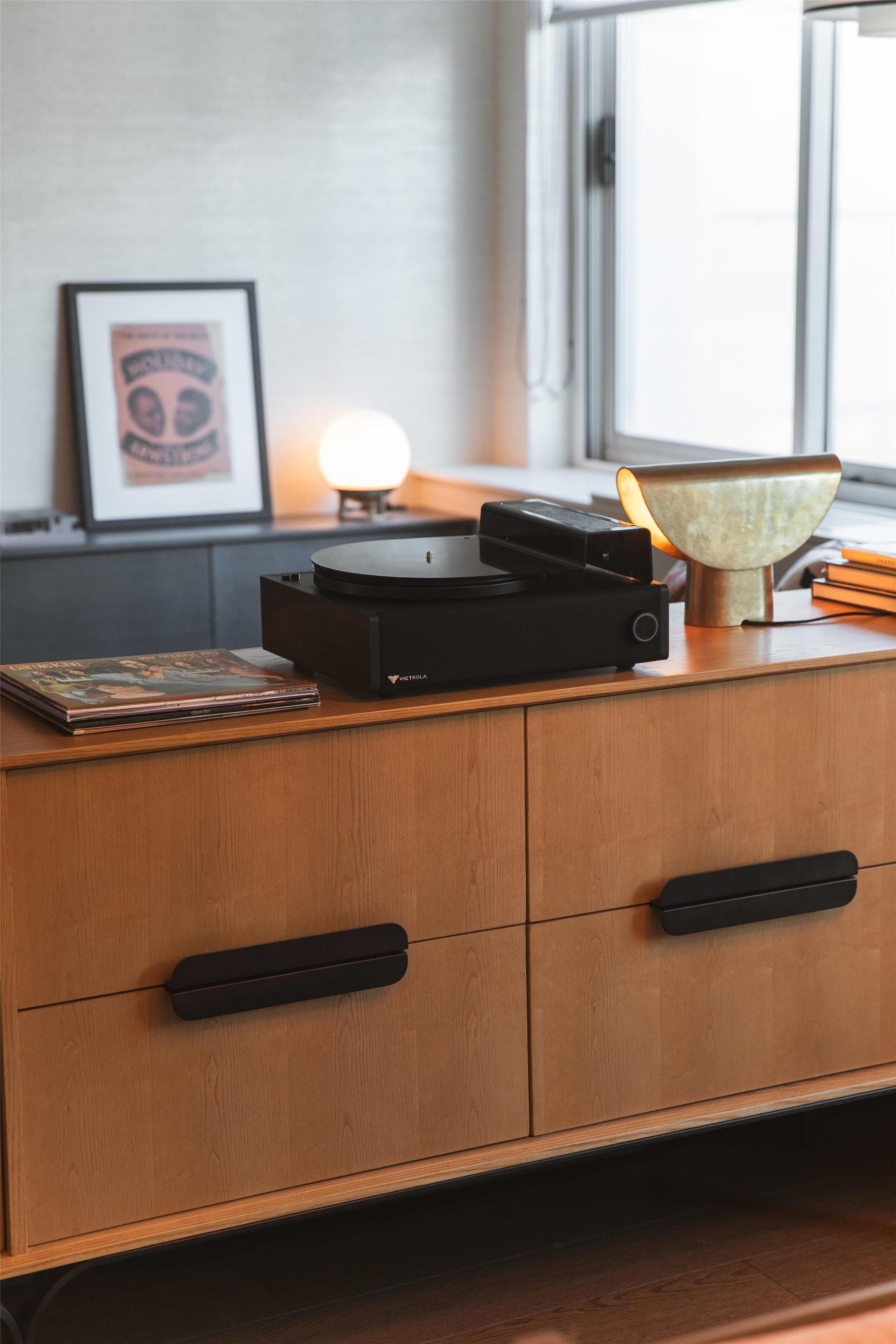 A wooden cabinet with a turntable and books on top.