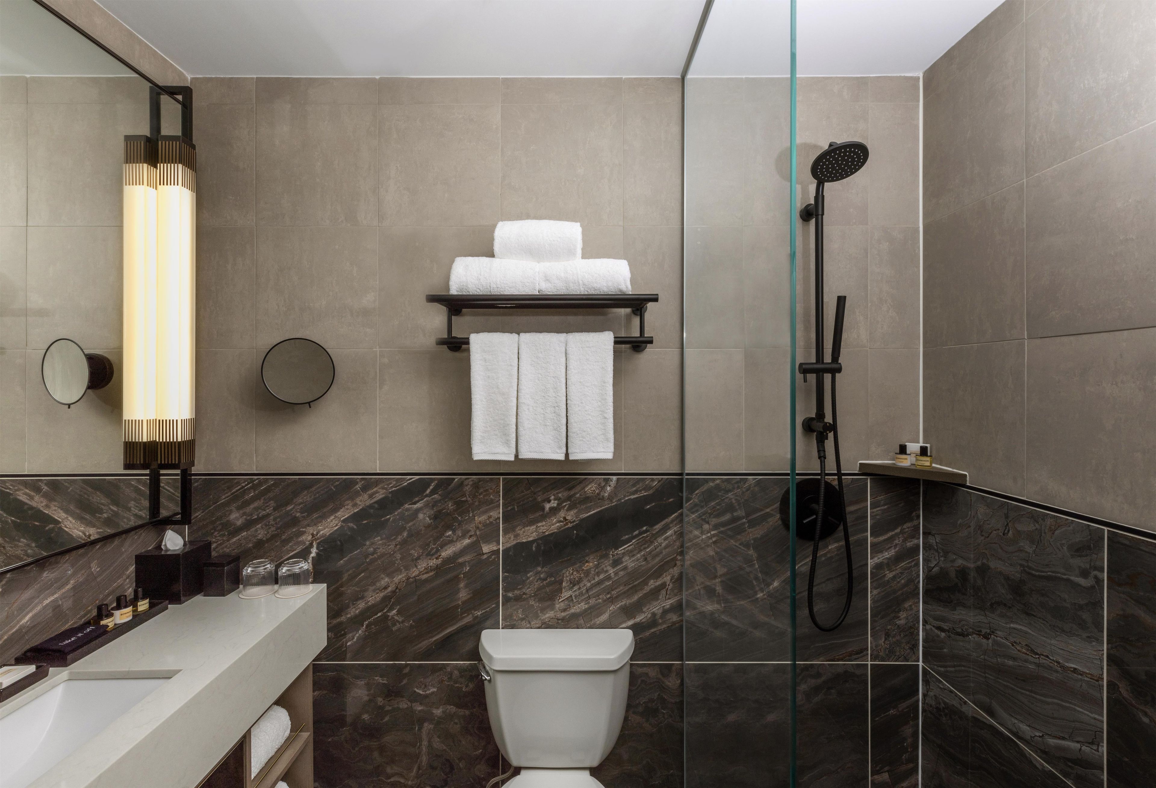 A modern bathroom with a toilet, a shower, and a towel rack.