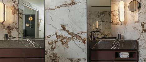 A bathroom with a marble vanity, a mirror, a towel rack, and a modern light fixture.