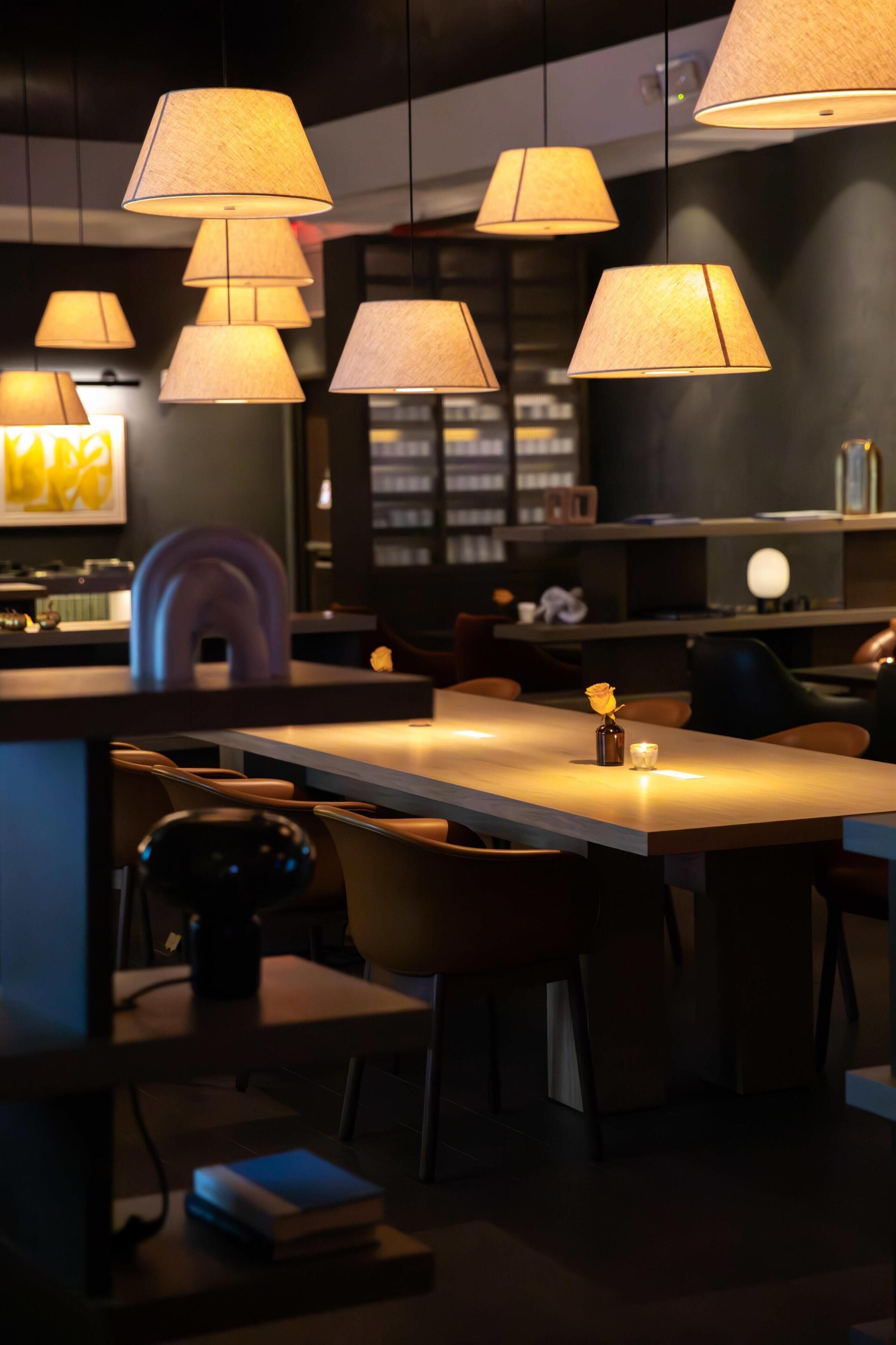 Um interior moderno com iluminação pendente, uma mesa central e assentos.