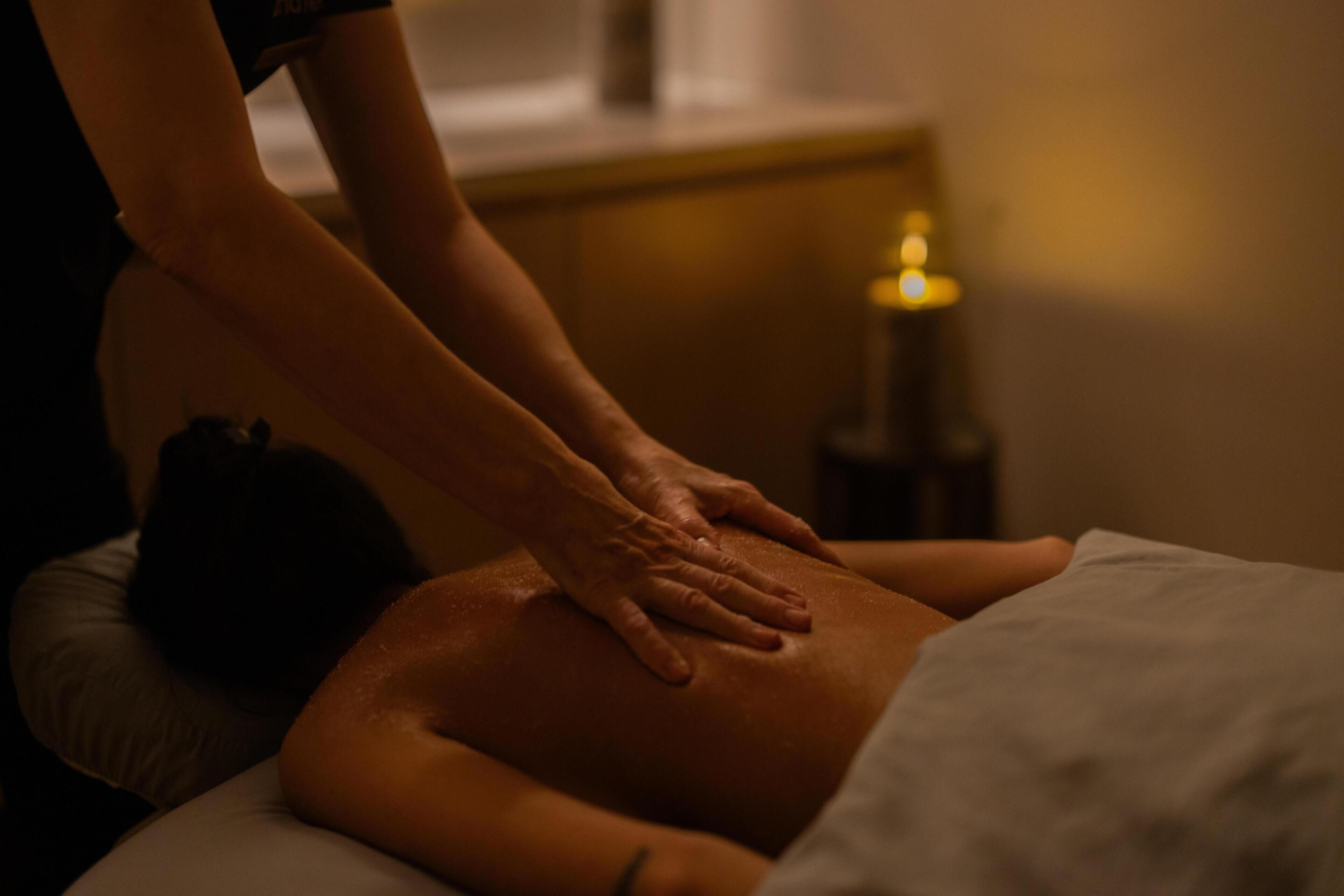 A massage therapy session in a dimly lit room with a candle on a table.