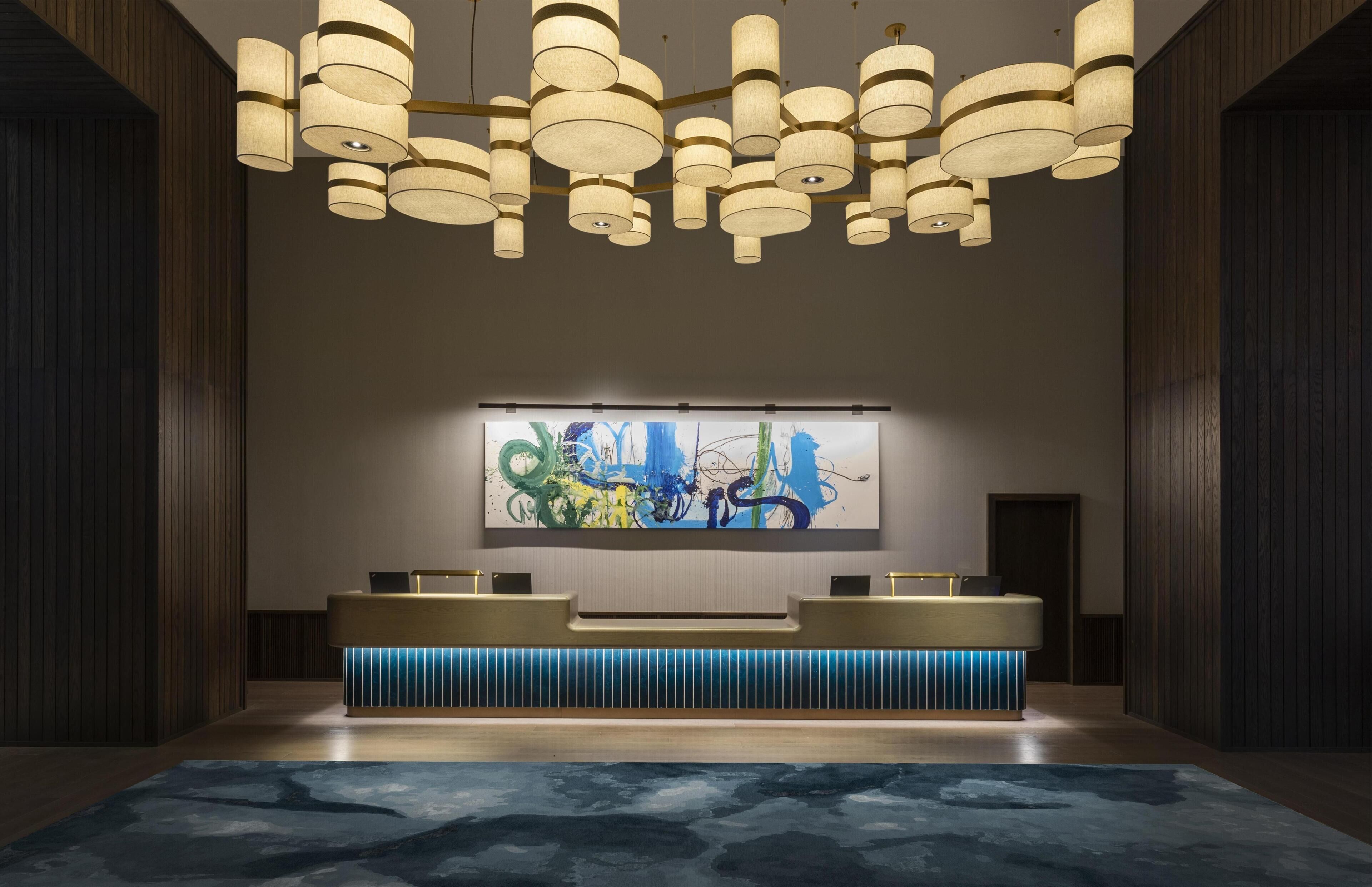 Eine moderne Lobby mit einer Rezeption, abstrakter Kunst und einem gemusterten Teppich.
