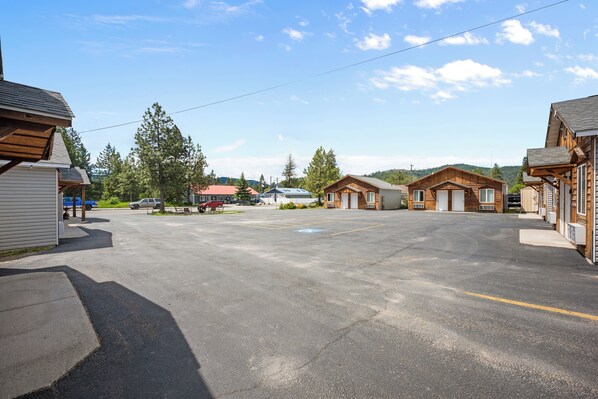 A parking lot with several wooden buildings, some with attached garages, and a few vehicles parked.