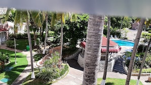 A pool area with a slide, palm trees, and a stone pathway. - Fisherman's Point Apartments (Ocho Rios)