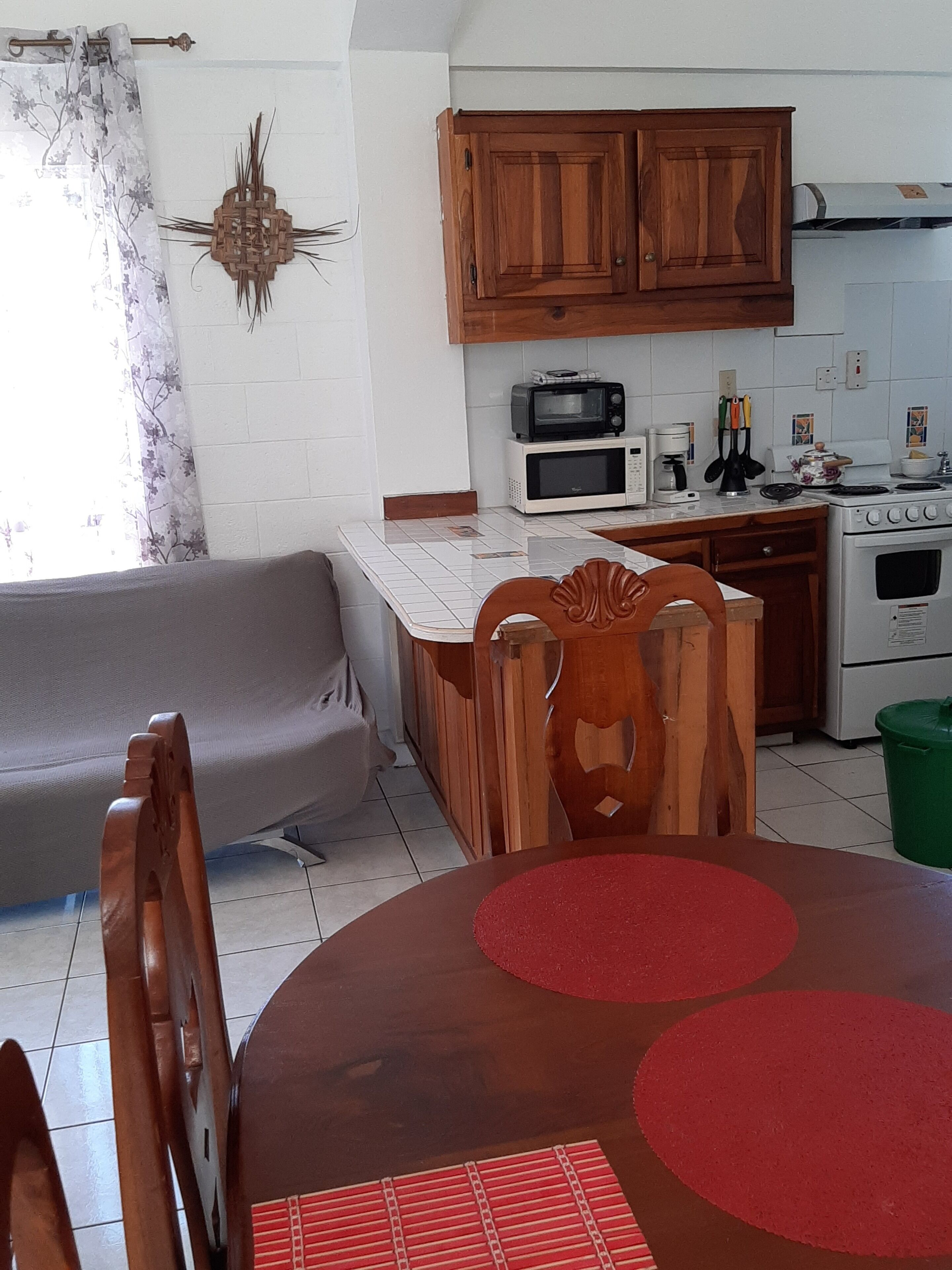 A compact kitchen with wooden cabinets, a microwave, a stove, and a dining area with a table and chairs.