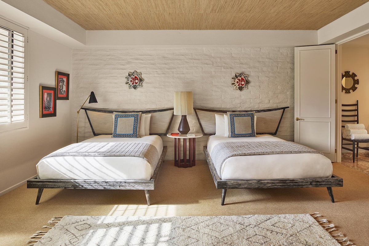 Ein Schlafzimmer mit zwei Betten, einer Holzbalkendecke, einer Backsteinwand und einer Tür.