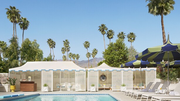 A pool area with lounge chairs, a covered seating area, and palm trees in the background. - Parker Palm Springs (Palm Springs)
