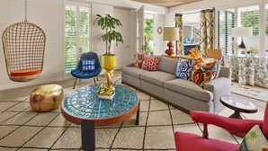 A living room with a hanging chair, a round coffee table, a sofa, and a red armchair. - Parker Palm Springs (Palm Springs)