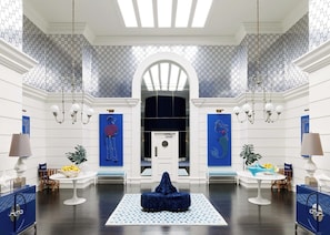 A spacious lobby with a central seating area, a high ceiling with skylights, and a patterned wall design.