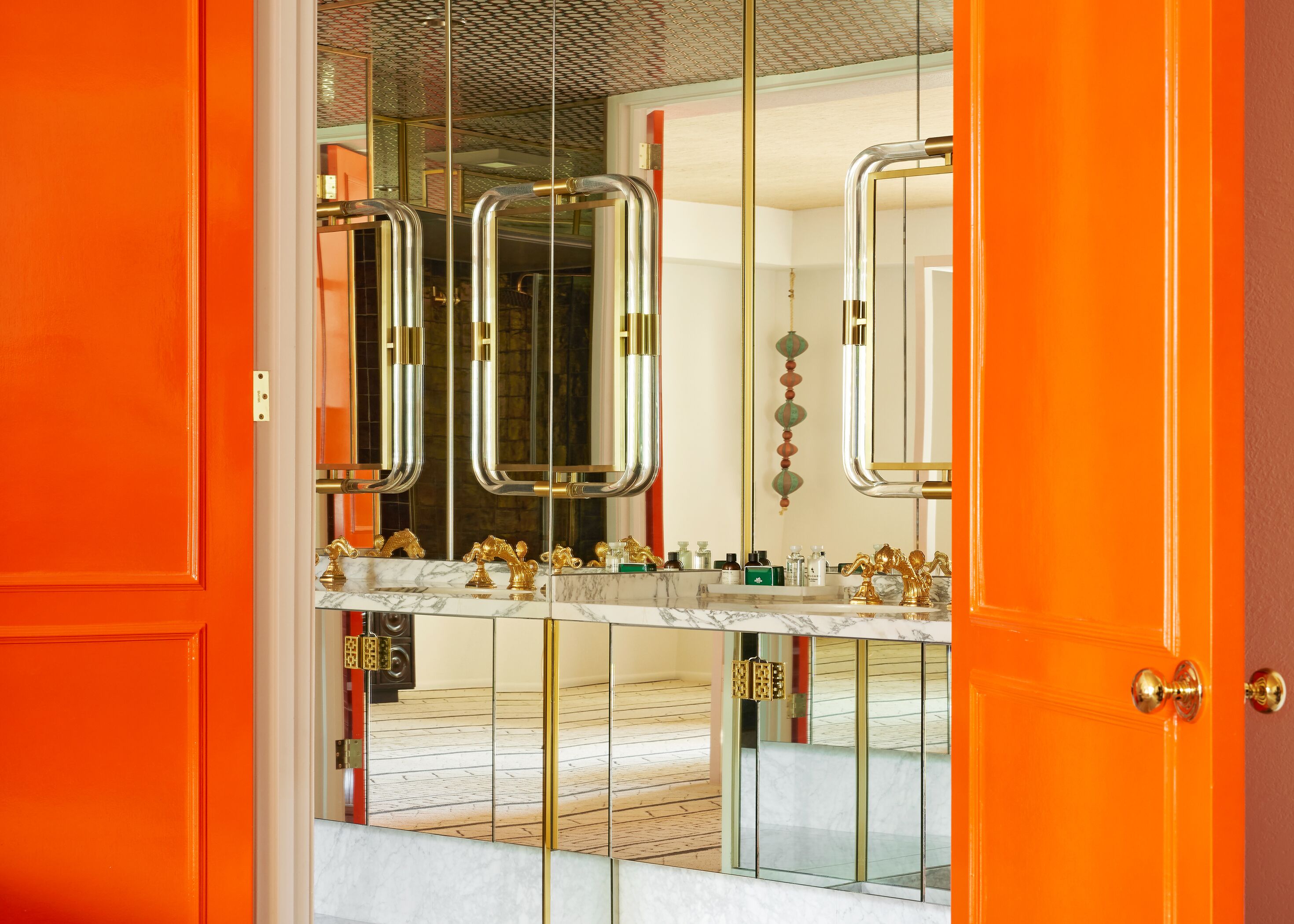 Ein Badezimmer mit Marmor-Waschtisch, goldenen Armaturen und einem großen Spiegel.