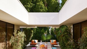 A modern outdoor patio with a wooden deck, colorful cushions, and a central table with a bowl of oranges. - Parker Palm Springs (Palm Springs)