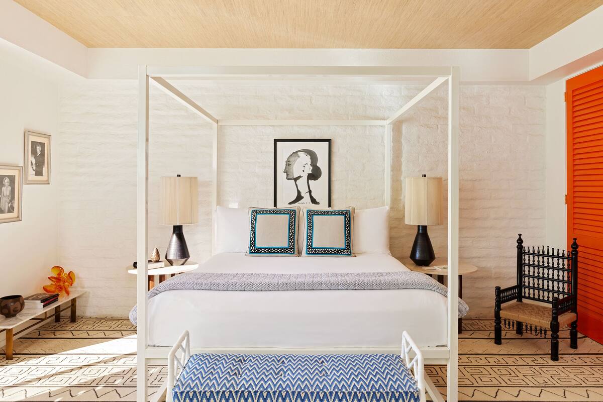 Ein Bett mit Baldachin, zwei Nachttischlampen und ein gerahmtes Kunstwerk darüber.