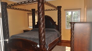 Un letto a baldacchino con struttura in legno scuro e copripiumino trapuntato.