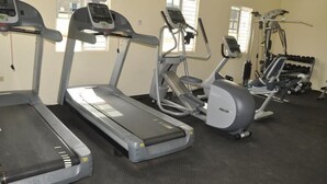 Un gimnasio con cintas de correr, elípticas y equipo de pesas.