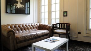 A room with a brown leather sofa, a wooden chair with a striped cushion, and a white coffee table.