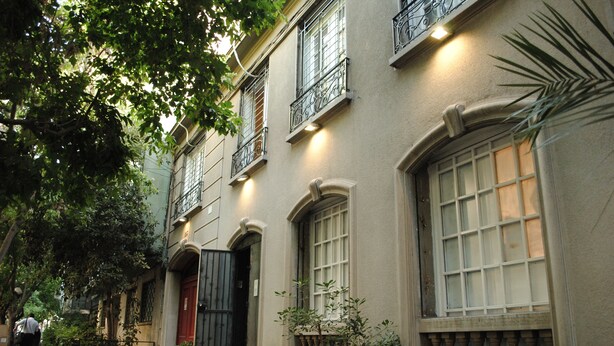 A building with multiple windows, a red door, and a balcony with a balustrade.