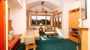 A cozy room with a wooden bench, a table, a sofa, and a cabinet. - Mendocino View East (Mendocino)