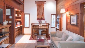 A cozy cabin interior with a dining area, a sofa, and wooden walls.
