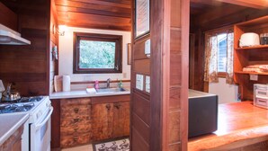 A compact kitchen with wooden cabinets, a stove, a sink, and a microwave.