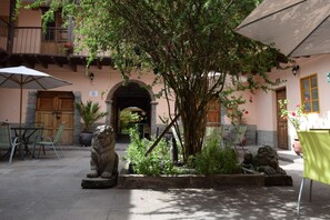 Une cour avec des statues de lions en pierre, une porte en bois et une table entourée de chaises.