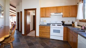 A kitchen with wooden cabinets, a stove, and a dishwasher. - Mendocino View West (Mendocino)