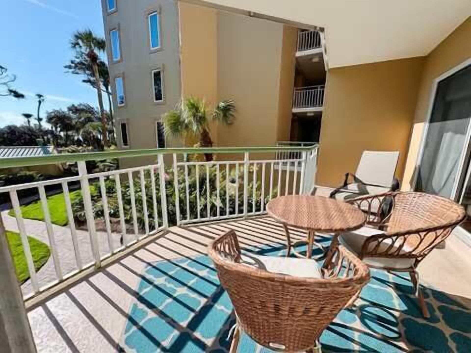 A balcony with wicker furniture and a glass railing.