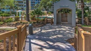 A resort with a pool, wooden deck, and a gated entrance.