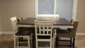 A dining area with a rectangular table and four chairs, a window with blinds, and a ceiling light. - Awesome remodeled house! (Mentor)