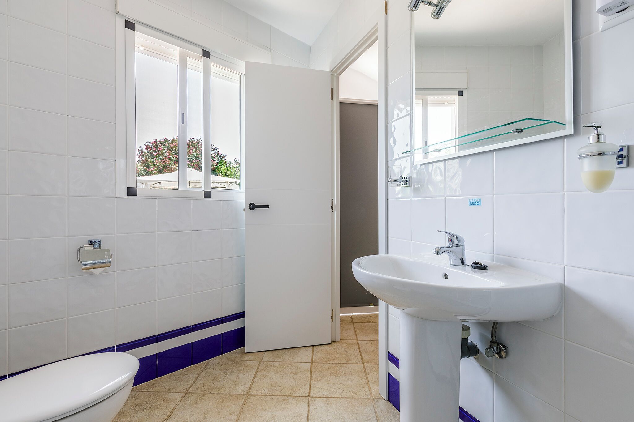 A modern bathroom with a toilet, sink, and a window.