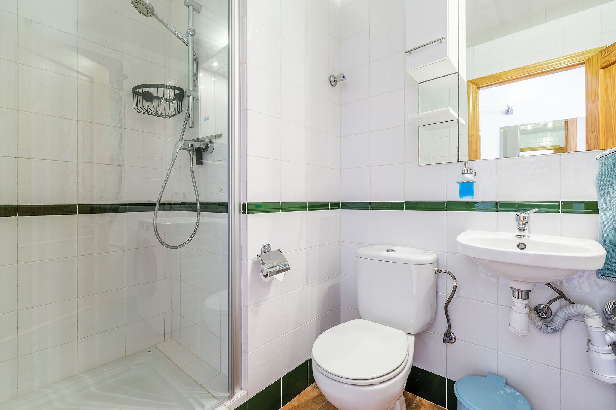A bathroom with a shower, toilet, sink, and a mirror.
