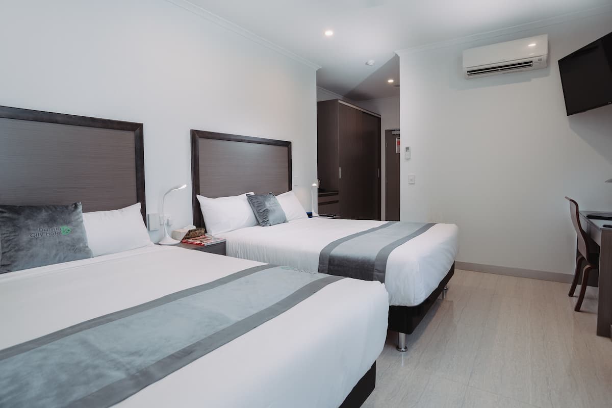 Une chambre d’hôtel avec deux lits, un bureau et un appareil de climatisation.