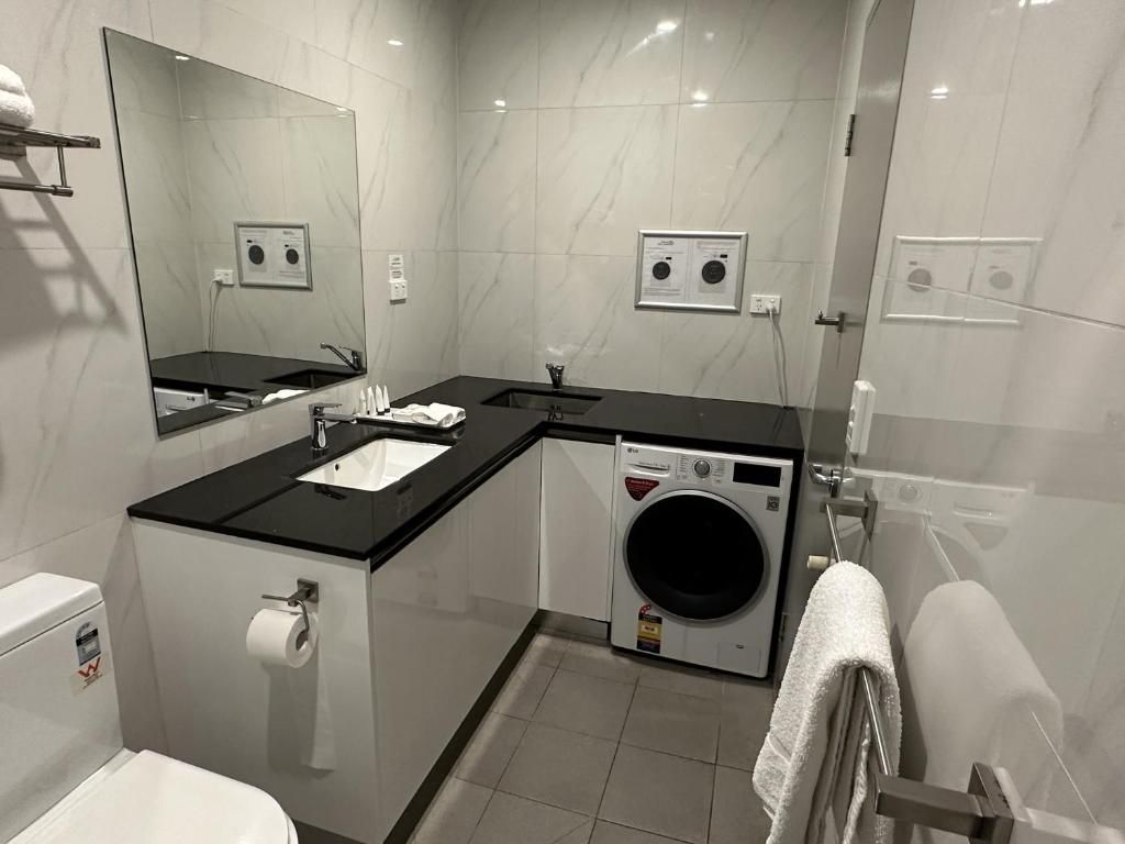 Un baño moderno con inodoro, lavabo, espejo y lavadora integrada.