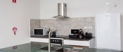 Una cocina moderna con campana de acero inoxidable, microondas, cafetera y refrigerador empotrado.