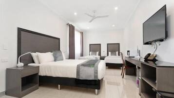 Una habitación de hotel moderna con una cama grande, un escritorio, un televisor y un ventilador de techo.