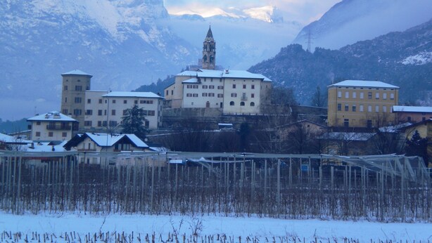 A snow-covered mountain town with historic buildings, including a prominent church with a tower.
