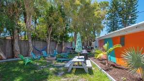 Ein Garten mit Holzzaun, Hängematte, Picknicktisch und Sitzbereich im Freien.