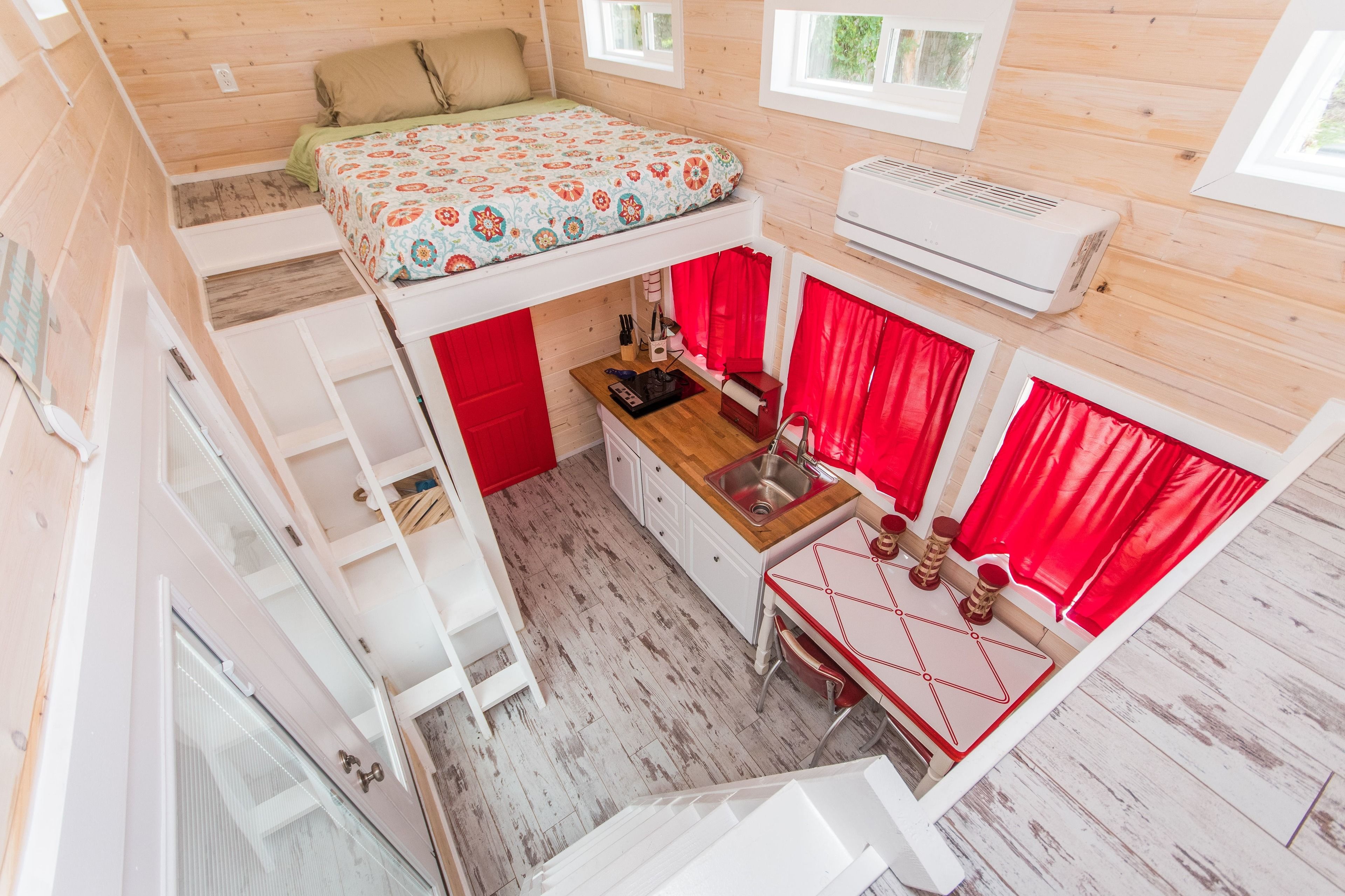 A compact, multi-level cabin with a bunk bed, kitchenette, and a small dining area.