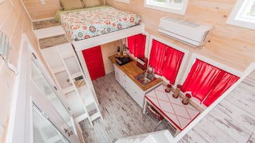 A compact, multi-level cabin with a bunk bed, kitchenette, and a small dining area.
