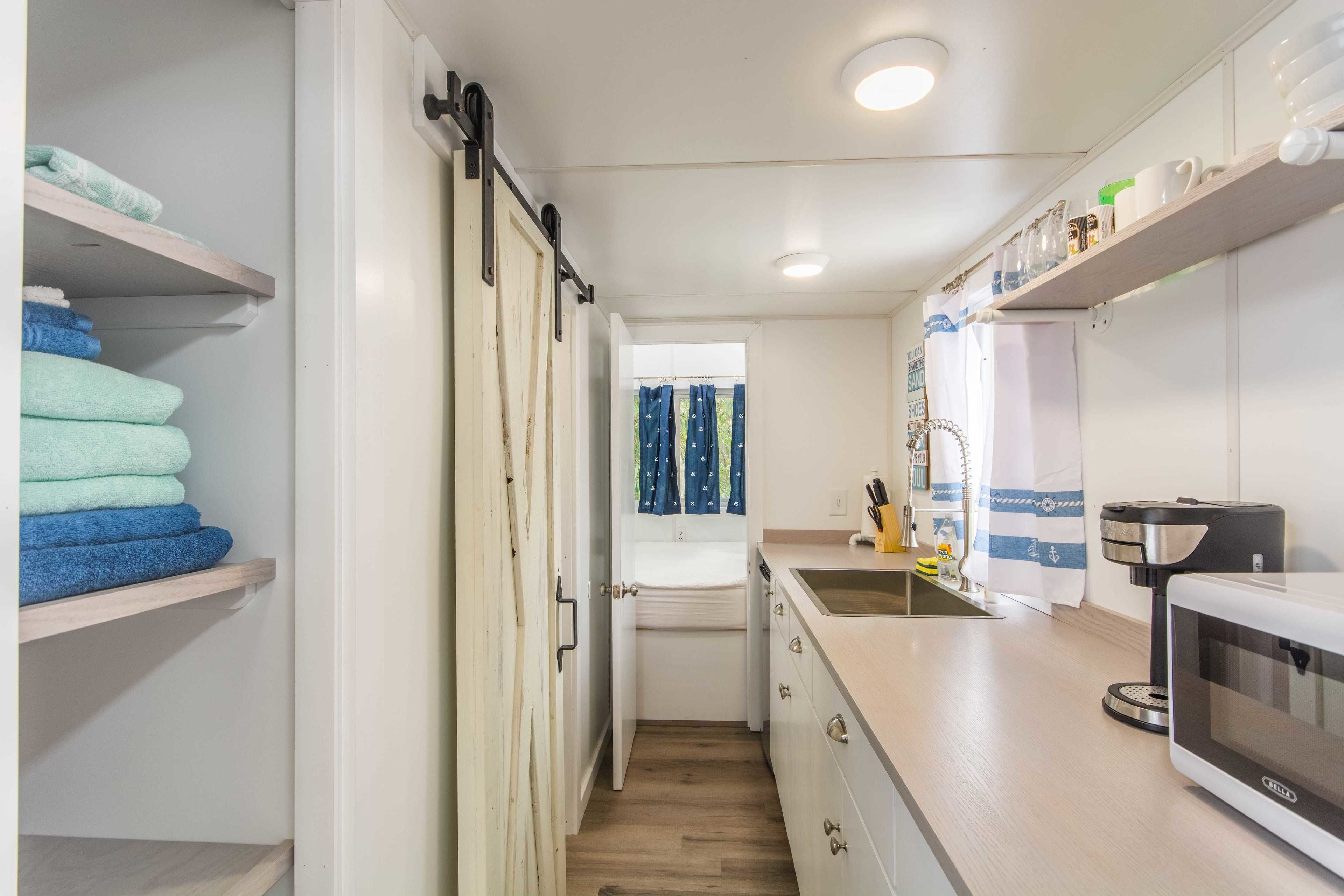 A compact kitchen with a microwave, coffee maker, and a window with curtains.