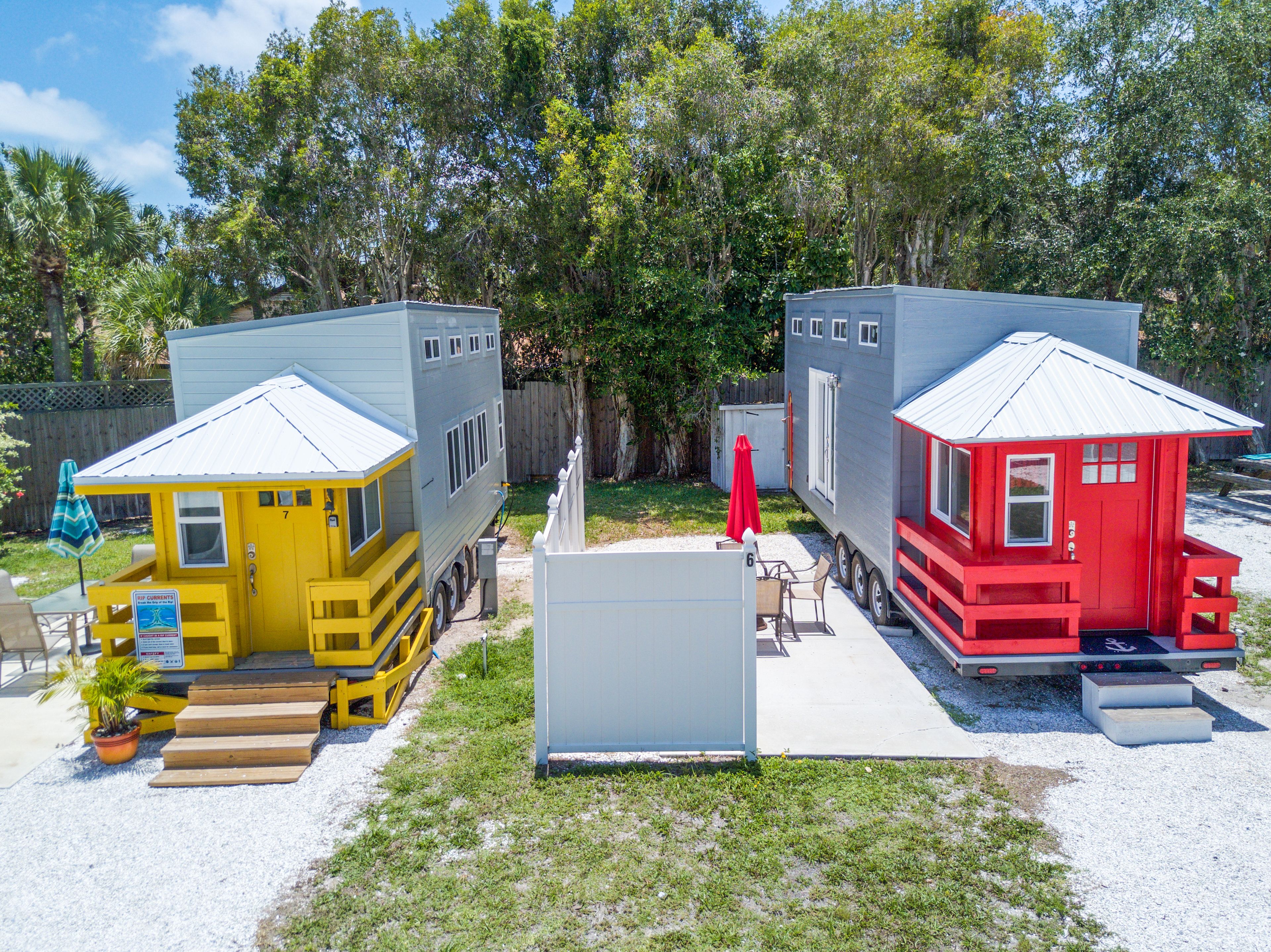 Two mobile homes, one yellow and one red, with a small shed in between.