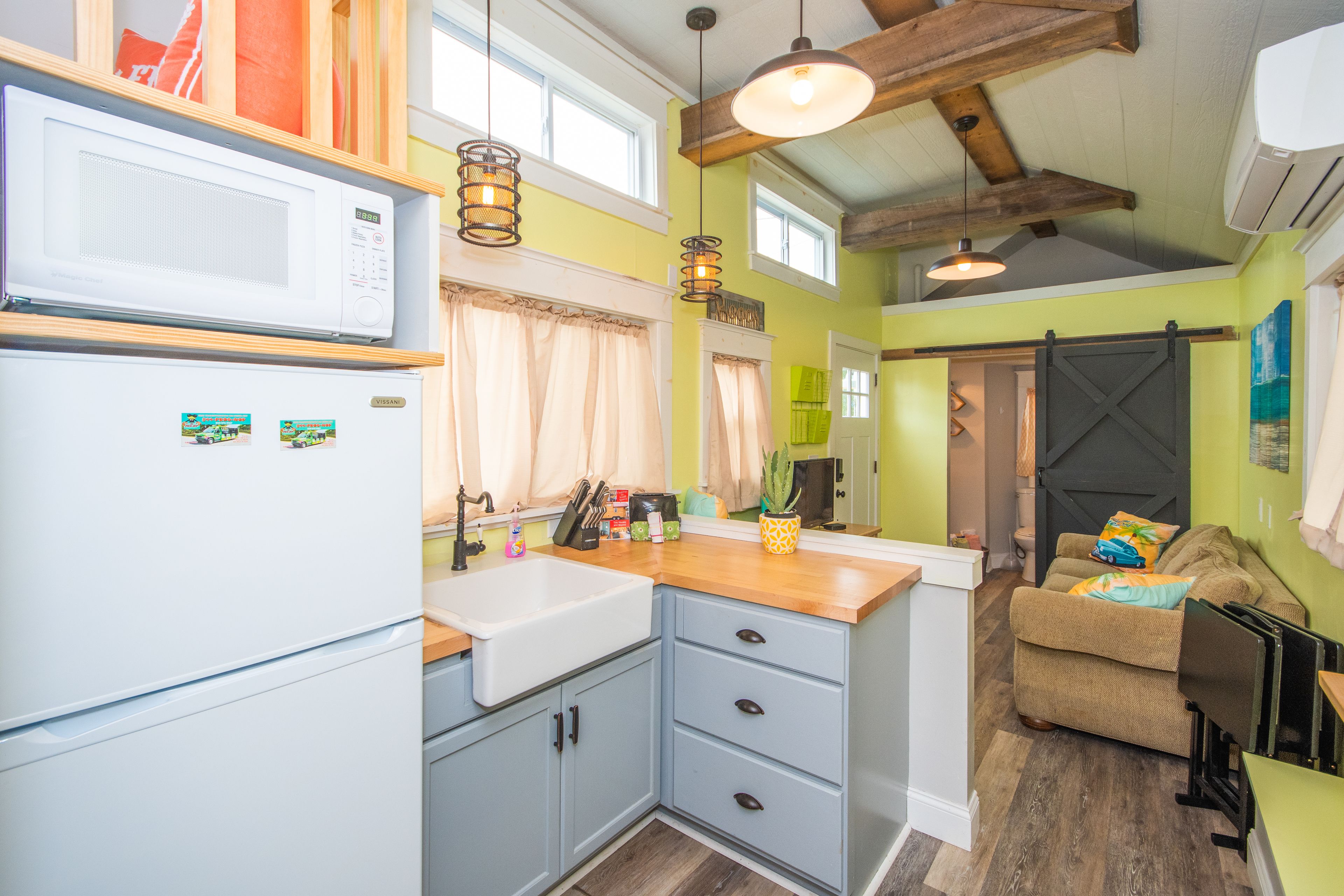 A compact kitchen with a microwave, sink, and wooden countertop.