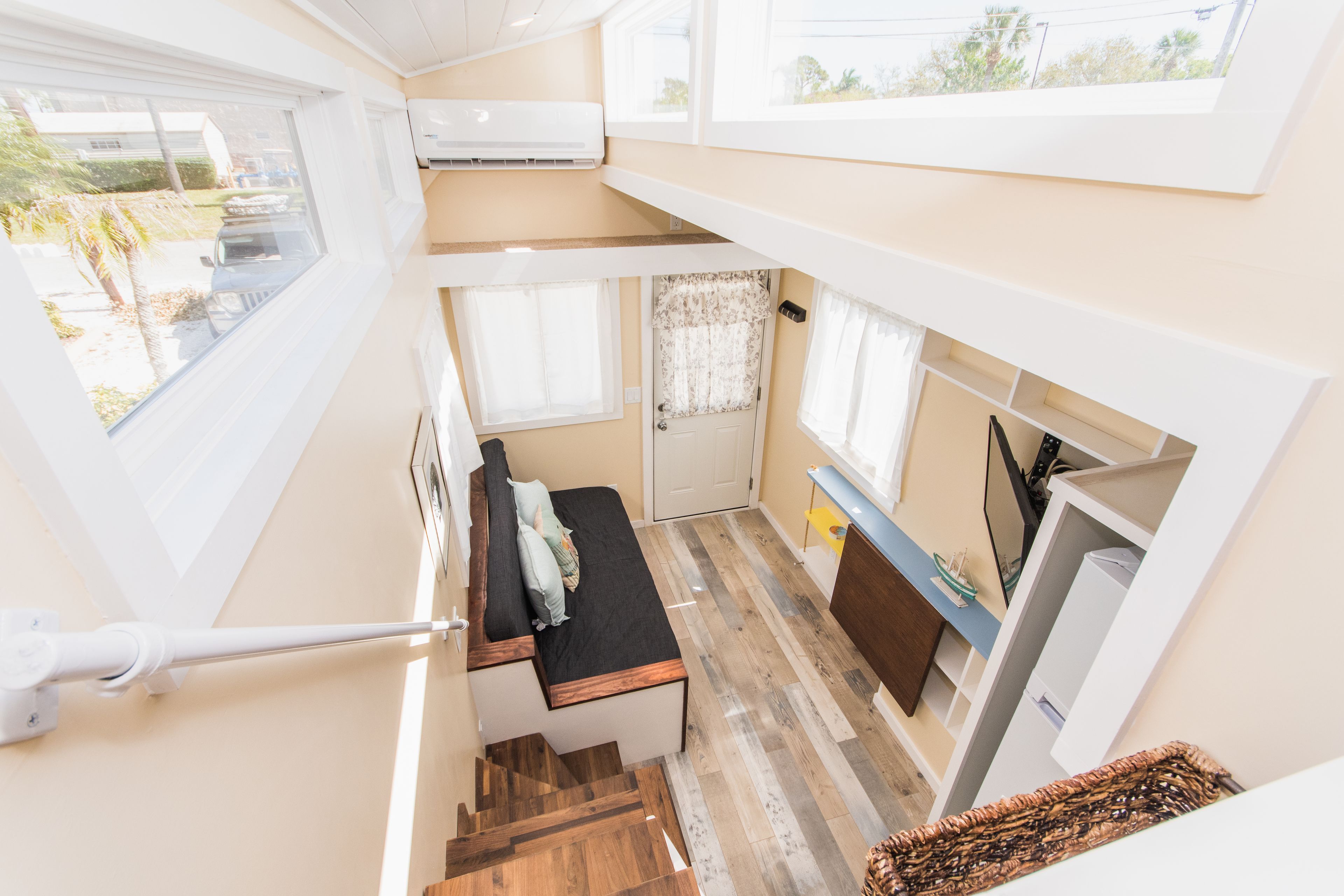 A compact, multi-level room with a loft bed, a small seating area, and a kitchenette.
