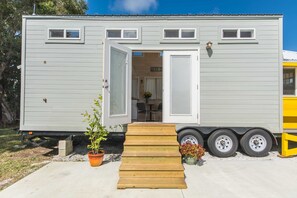 Ein Wohnmobil mit einer Holzrampe zum Eingang, einem Blumentopf und einem kleinen Garten.